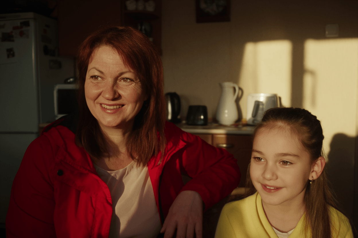 A middle-aged woman sitting beside her daughter in a cozy home kitchen
